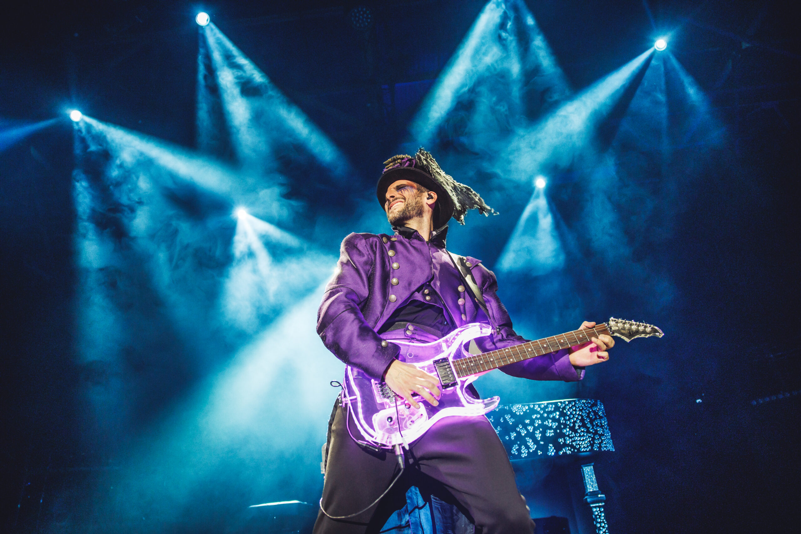 Guitarrista tocando bajo luces azules y guitarra eléctrica iluminada