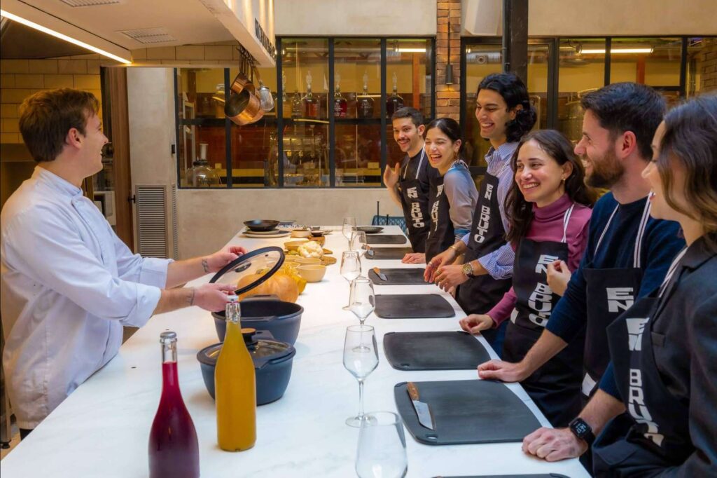 Clase de cocina interactiva con chef y asistentes en un ambiente social