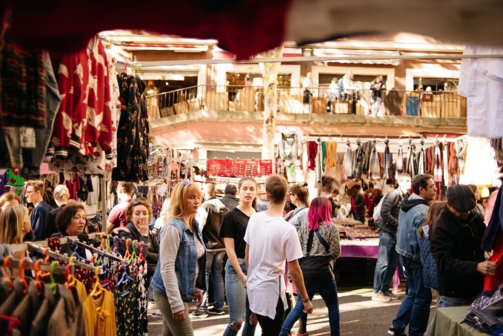 Mercado urbano al aire libre con puestos de ropa y ambiente animado