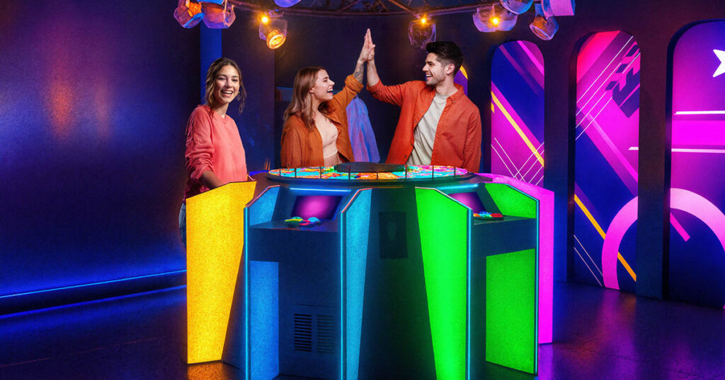 Amigos celebrando un reto superado en una experiencia interactiva con luces de colores
