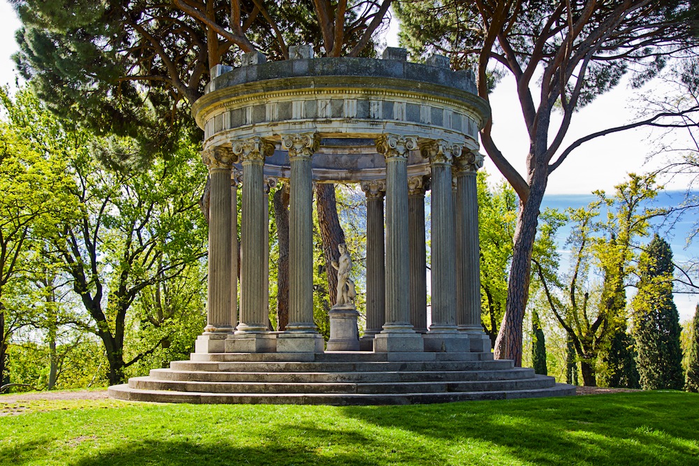 El Parque del Capricho de Madrid con un templete clásico rodeado de árboles y jardines verdes