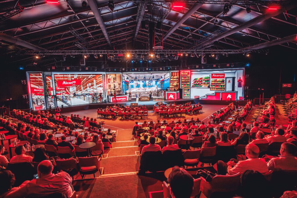Convención corporativa de Alcampo con gran aforo de asistentes presenciando un escenario con recreación inmersiva