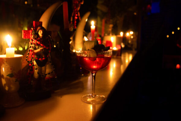 Cóctel servido en un ambiente nocturno con velas y decoración temática de misterio