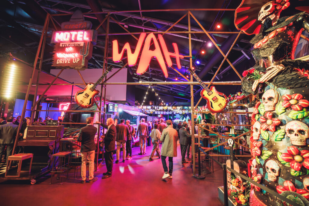 Interior del food hall WAH con decoración temática mexicana, luces de neón, guitarras colgantes y ambiente festivo en un espacio gastronómico