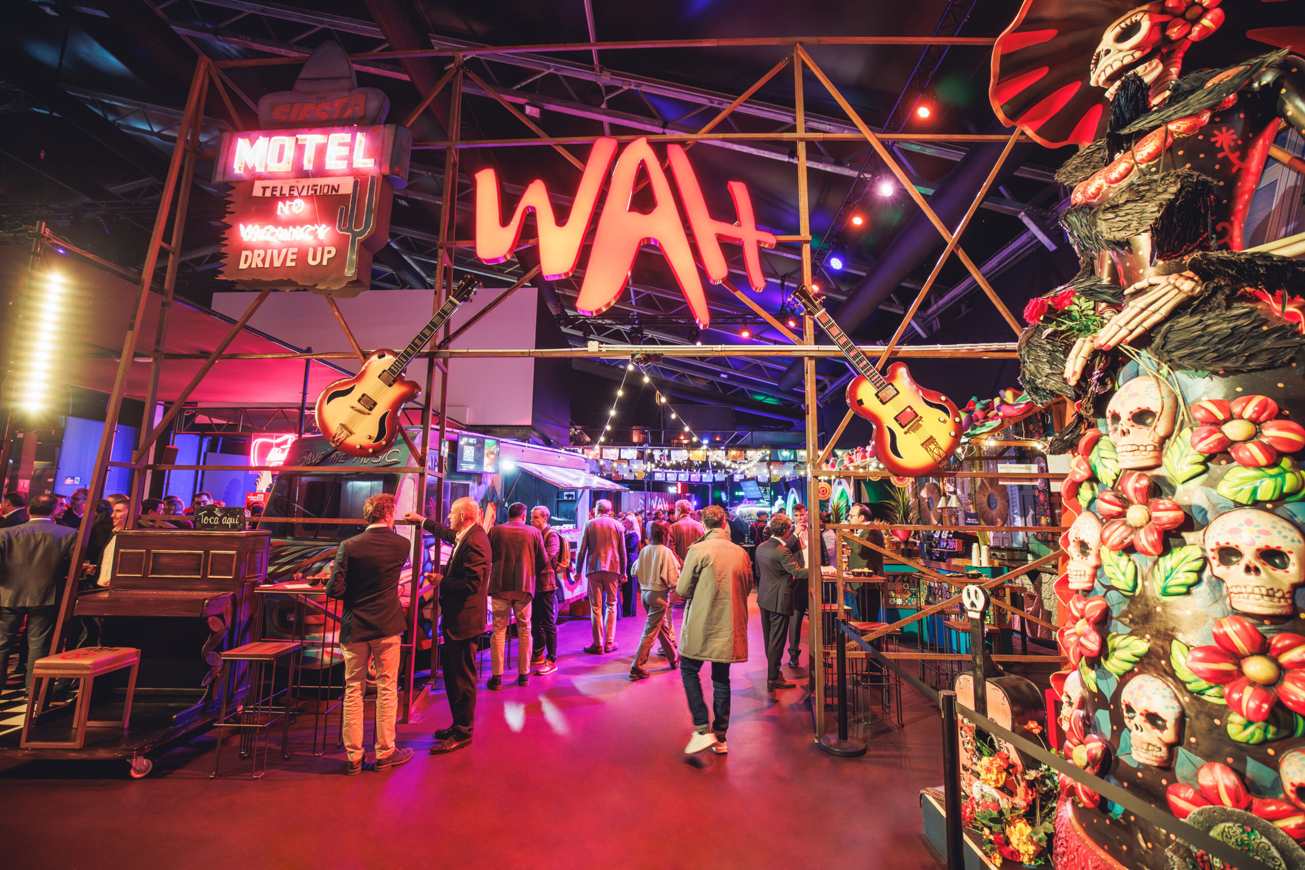Interior del food hall WAH con decoración temática mexicana, luces de neón, guitarras colgantes y ambiente festivo en un espacio gastronómico