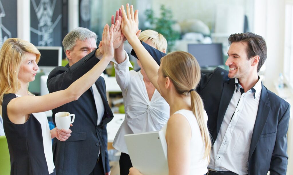 Compañeros brindando un high five tras una reunión de trabajo
