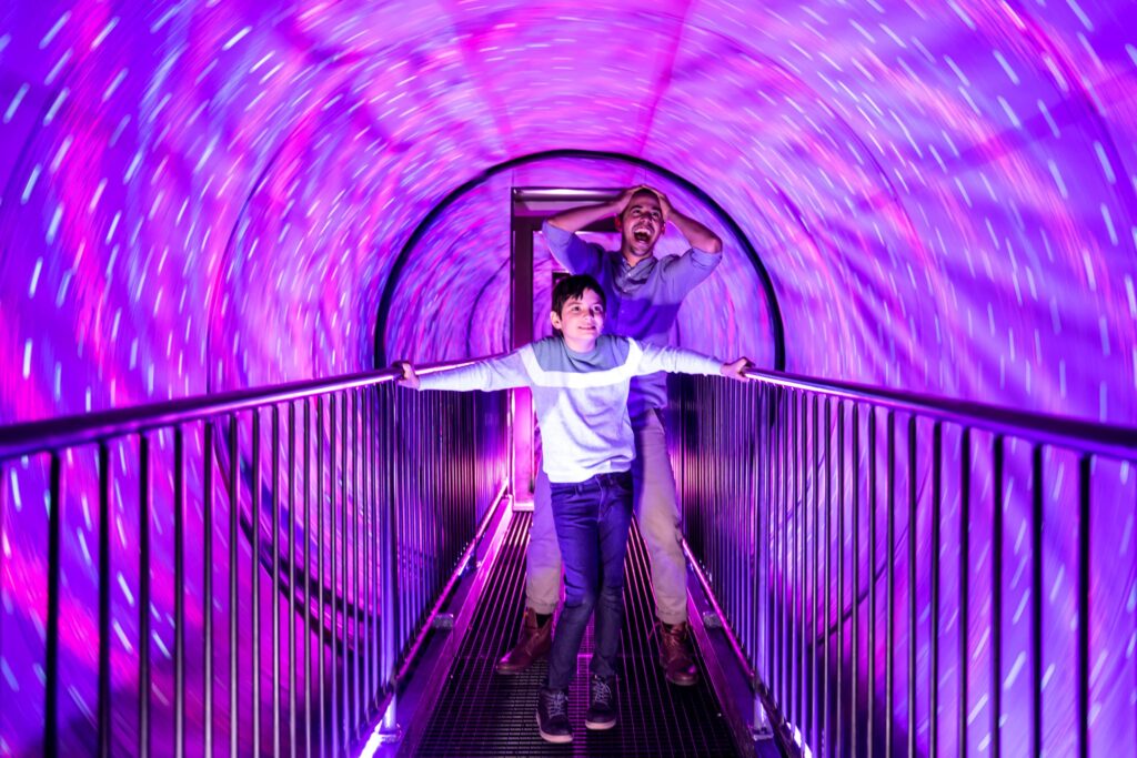 Túnel de luces con efectos visuales inmersivos donde adultos y niños experimentan ilusiones ópticas y sensaciones de movimiento