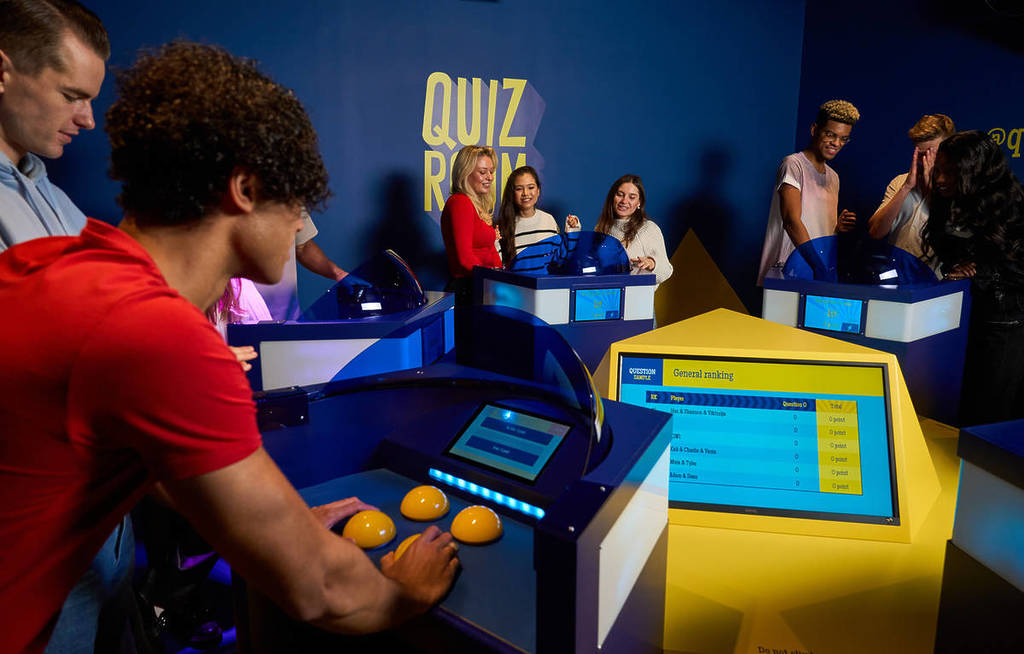 Grupo de participantes compitiendo en una actividad de team building tipo concurso en Quiz Room con pulsadores interactivos y pantalla de ranking en tiempo real