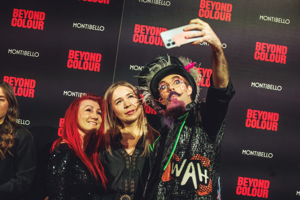 Actor de WAH Show en el evento Beyond Colour de Montibello posando con invitadas en un photocall.